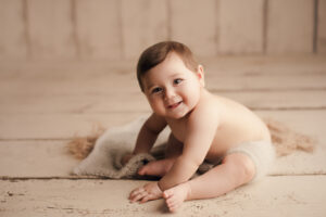 Portland Oregon Newborn Photographer, baby sitting on wooden floor looking at camera